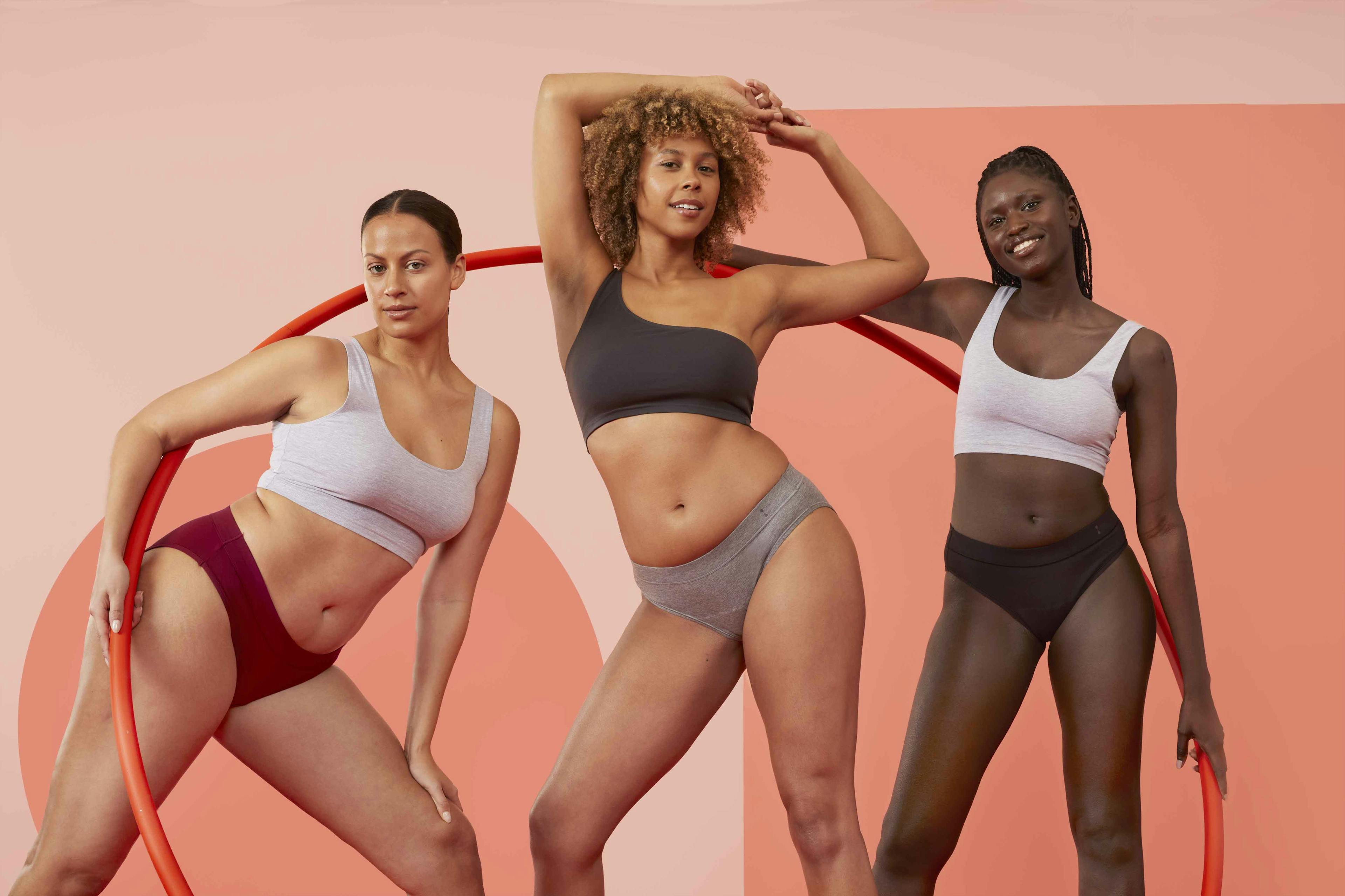 Three women standing next to each other in Thinx for All underwear smiling.