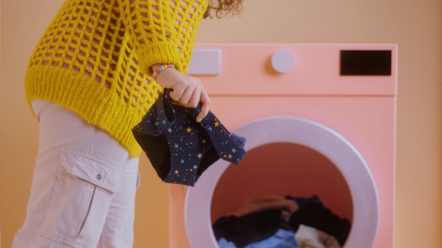 model holding period underwear in front of a washing machine